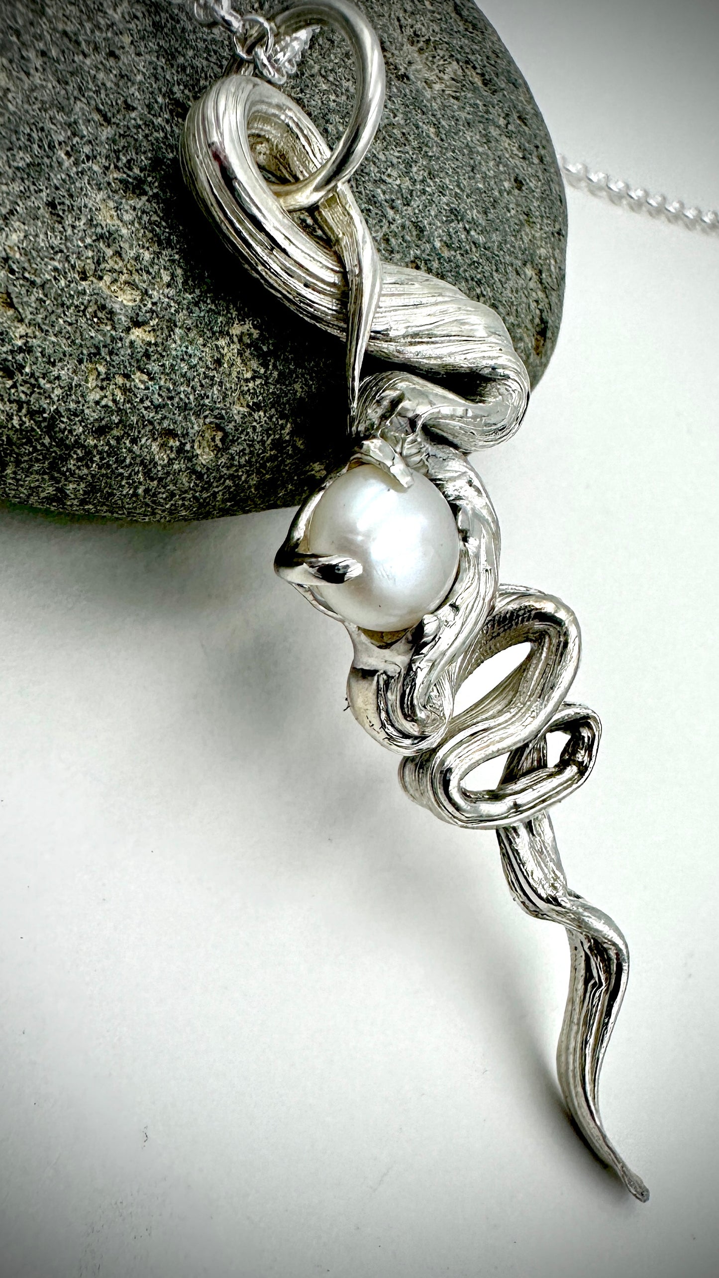 Close-up of Mitsuro Hikime flowing silver lines on statement trail pendant with white Freshwater Pearl