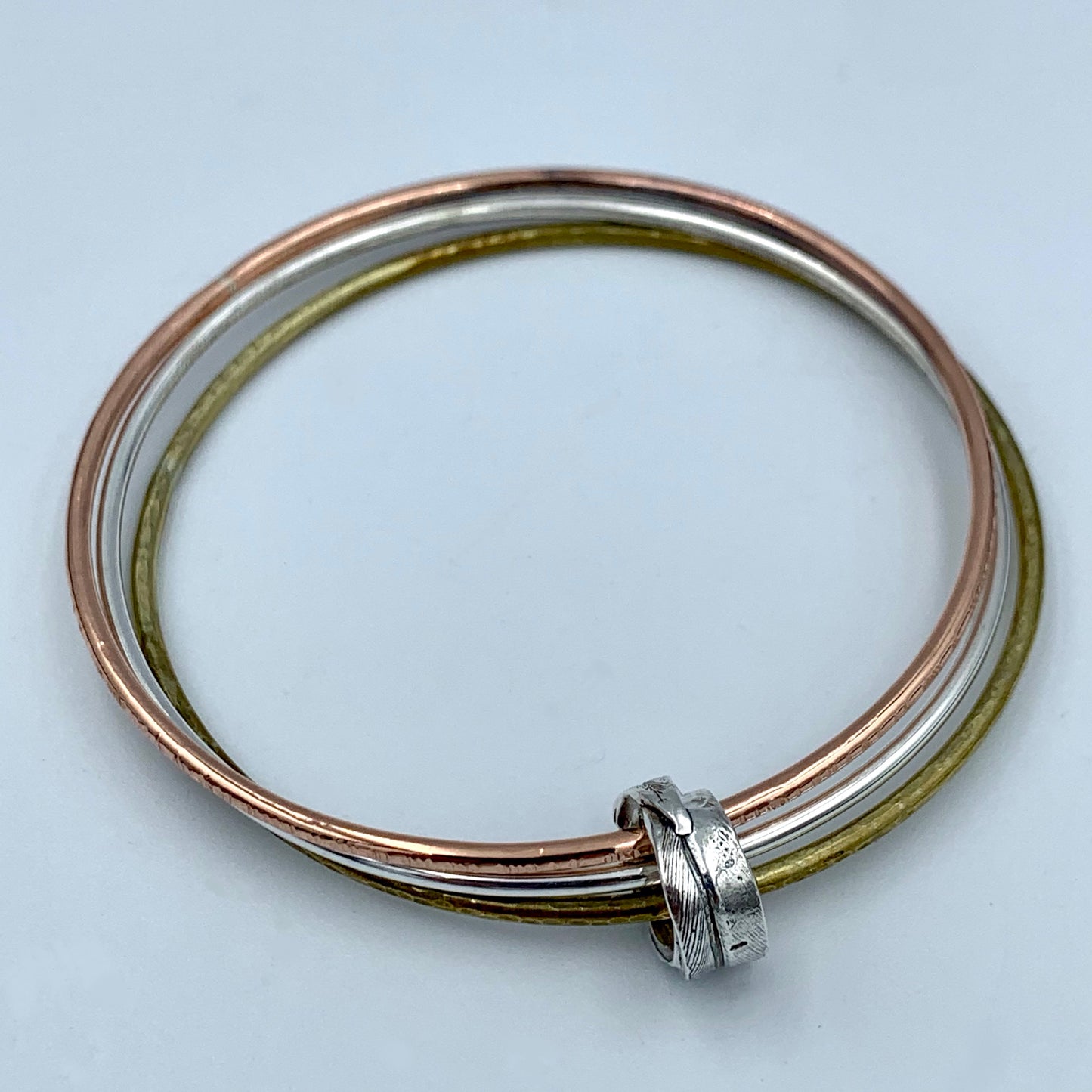Feather Bead Bangle triple set showing hammered brass and fine line hammered copper textures alongside polished sterling silver
