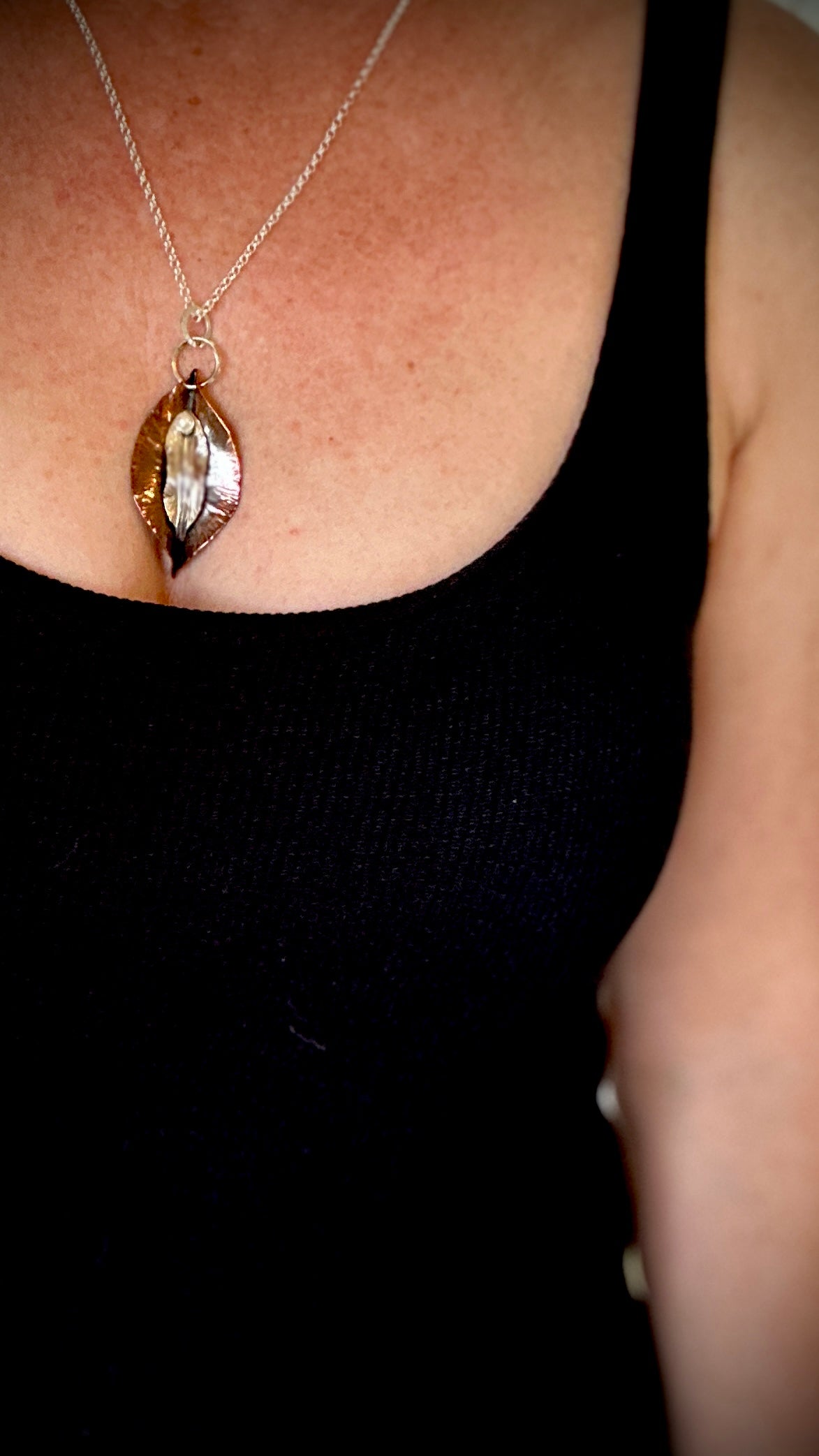 Hammered copper and sterling silver portal yoni pendant with freshwater pearl worn on décolletage over black top