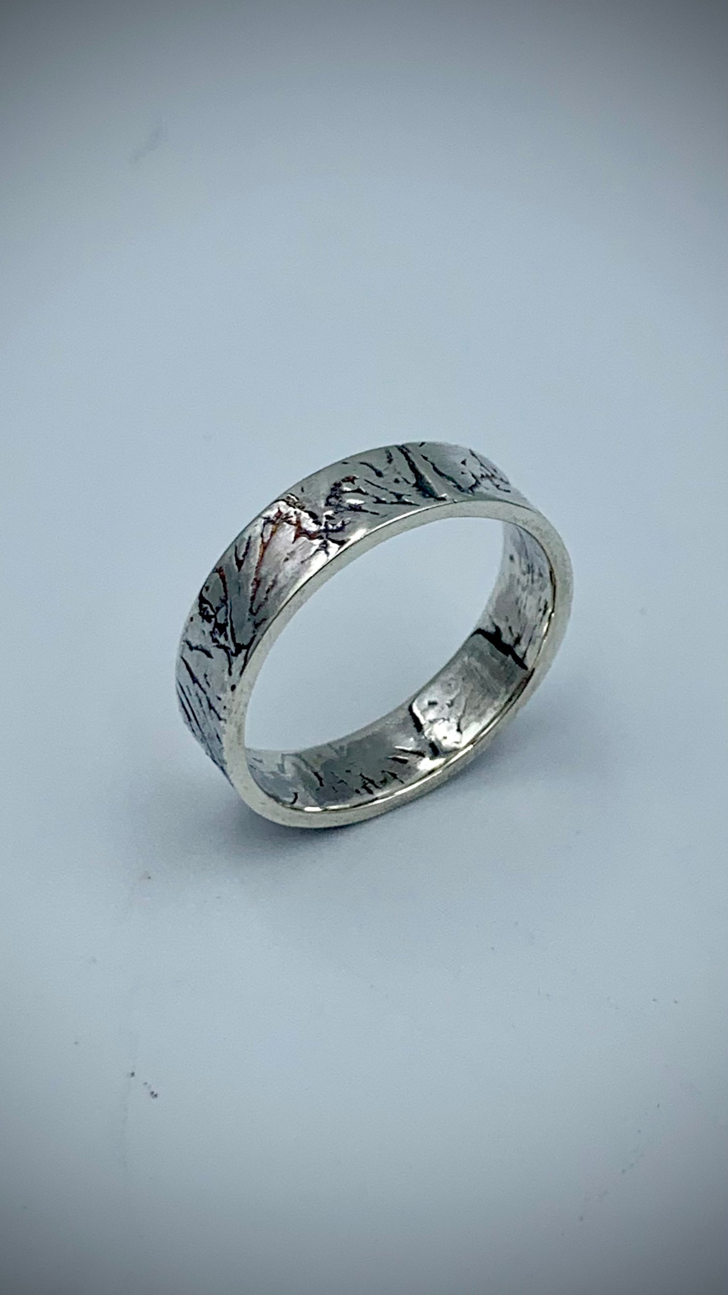 Handmade sterling silver band ring with Ginkgo Leaf texture, angled view on white background