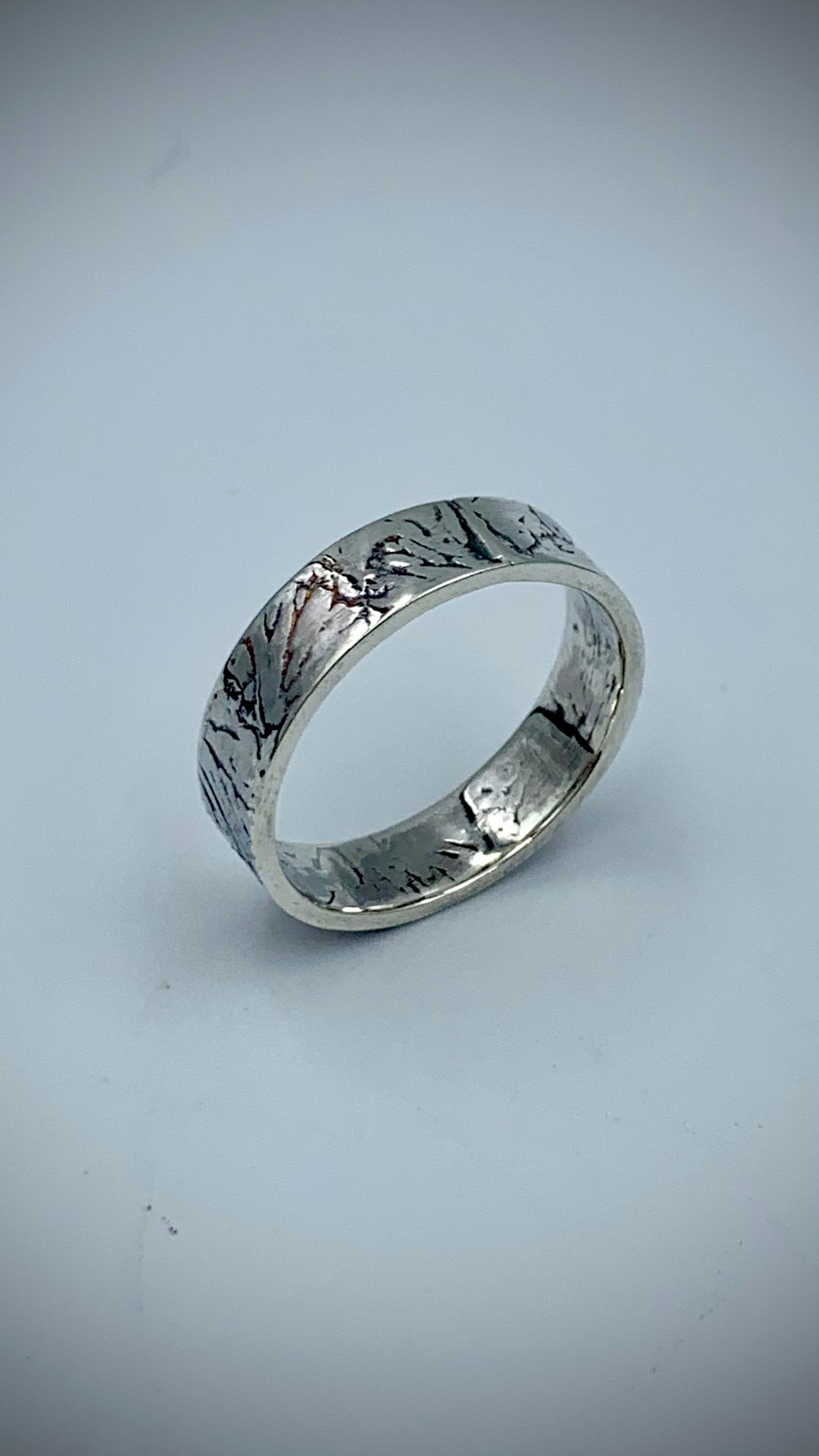 Handmade sterling silver band ring with Ginkgo Leaf texture, angled view on white background