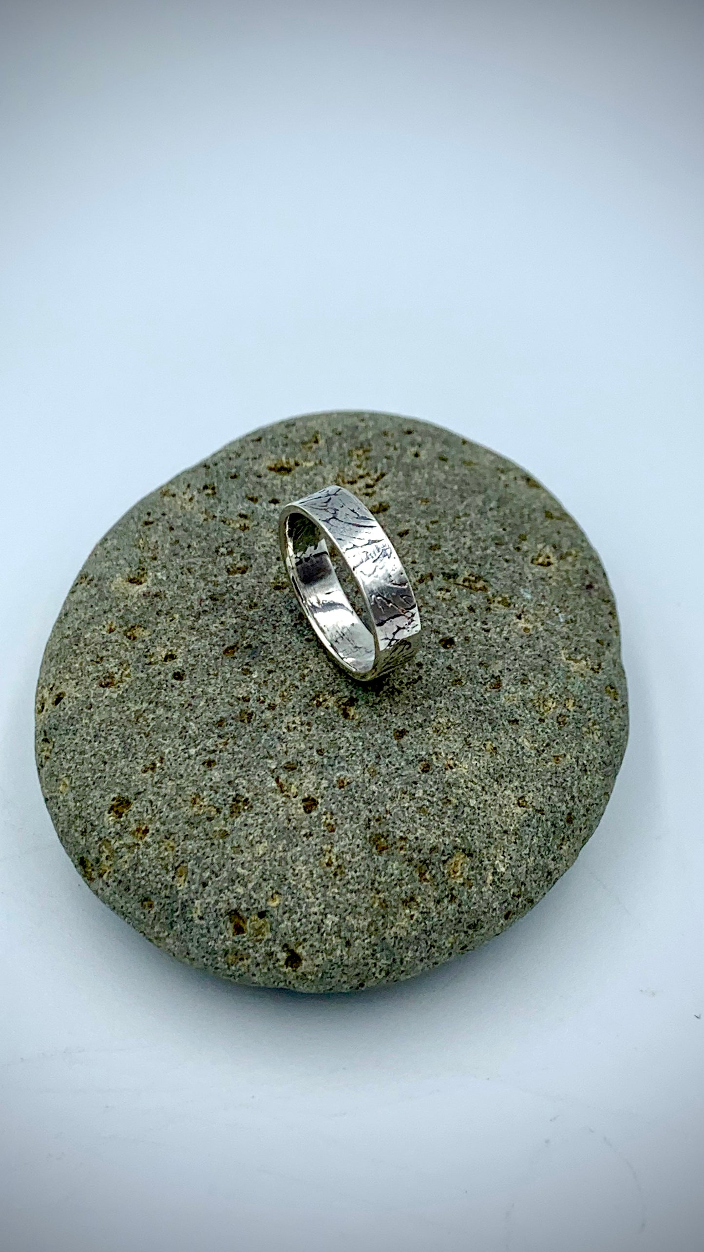 Side view of sterling silver Ginkgo Leaf stacking ring on grey river stone