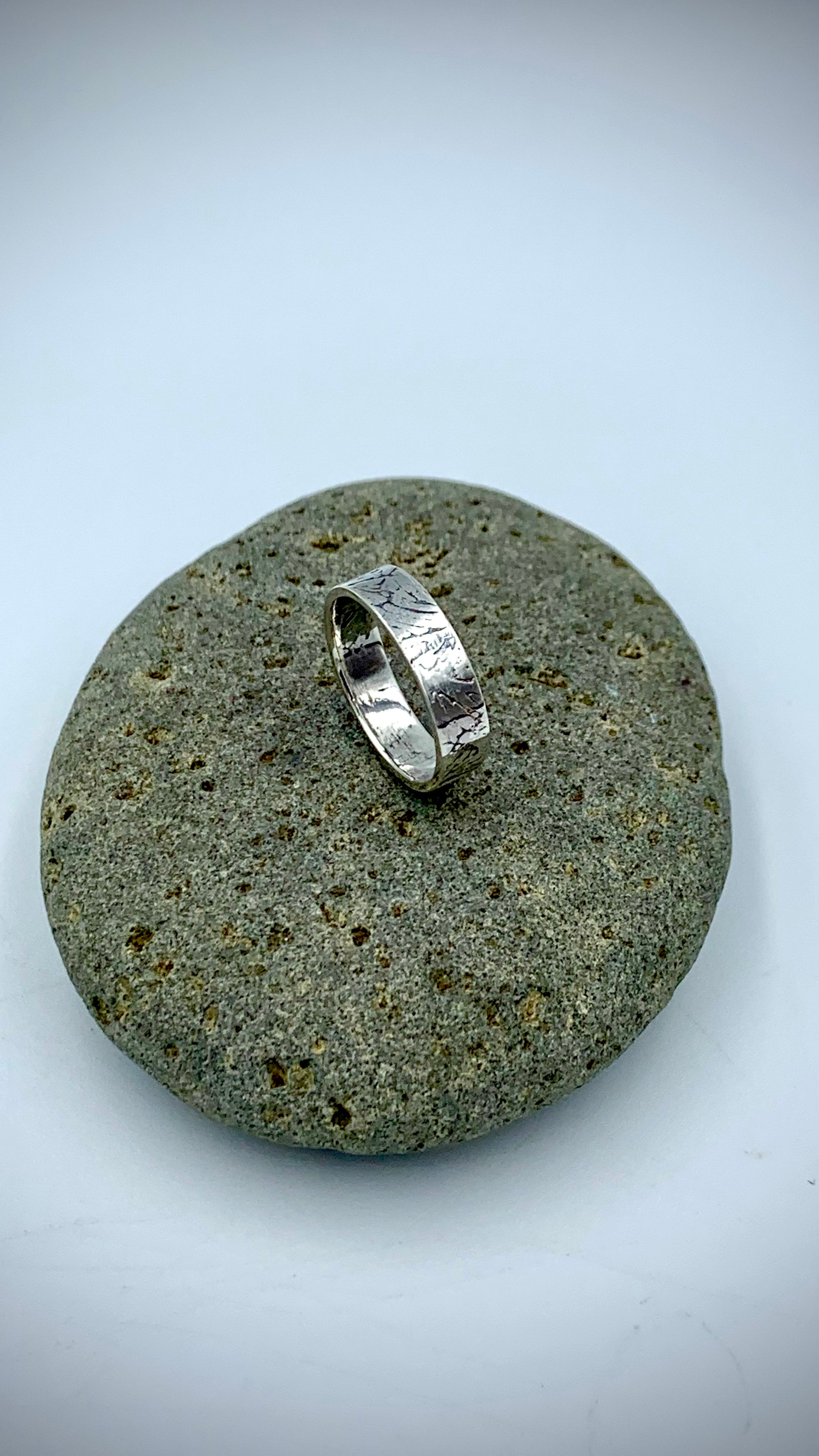 Side view of sterling silver Ginkgo Leaf stacking ring on grey river stone
