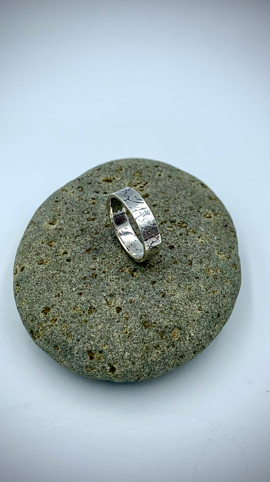 Side view of sterling silver Ginkgo Leaf stacking ring on grey river stone