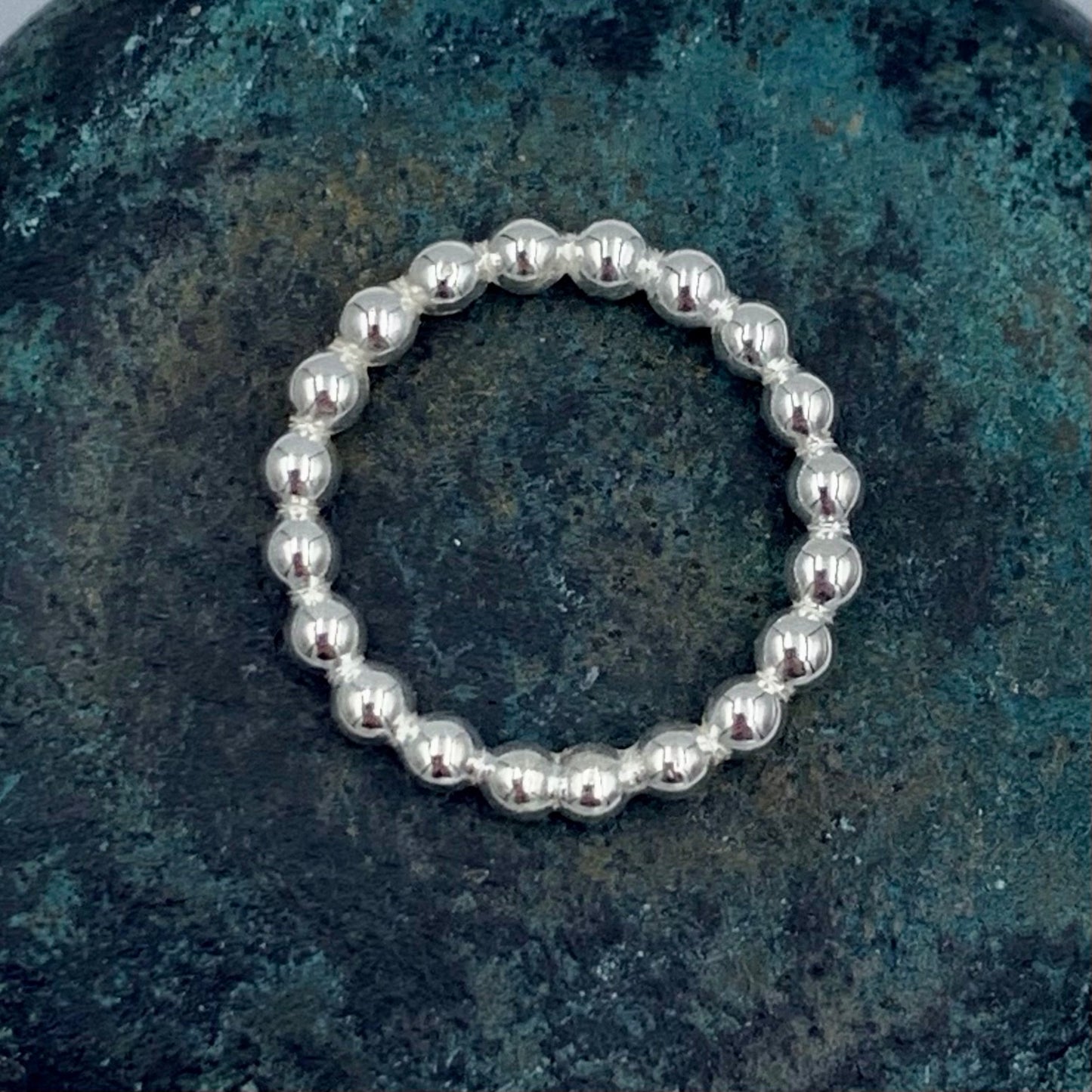 Sterling silver 3mm pearl bead stacking ring flat lay, top-down view 
