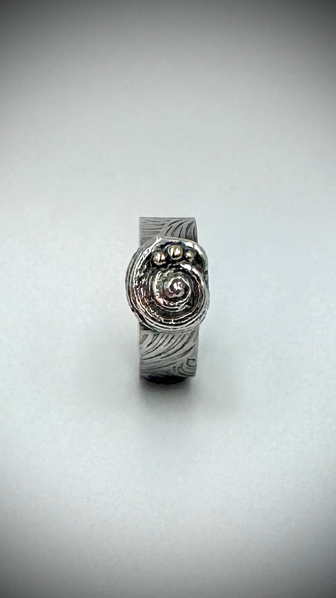 Sterling silver Beach Ring front view on white background, solid cast spiral shell centrepiece with three silver granules and wave-patterned wide band — Marina Fox Fine Art