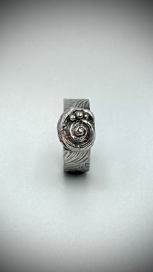 Sterling silver Beach Ring front view on white background, solid cast spiral shell centrepiece with three silver granules and wave-patterned wide band — Marina Fox Fine Art