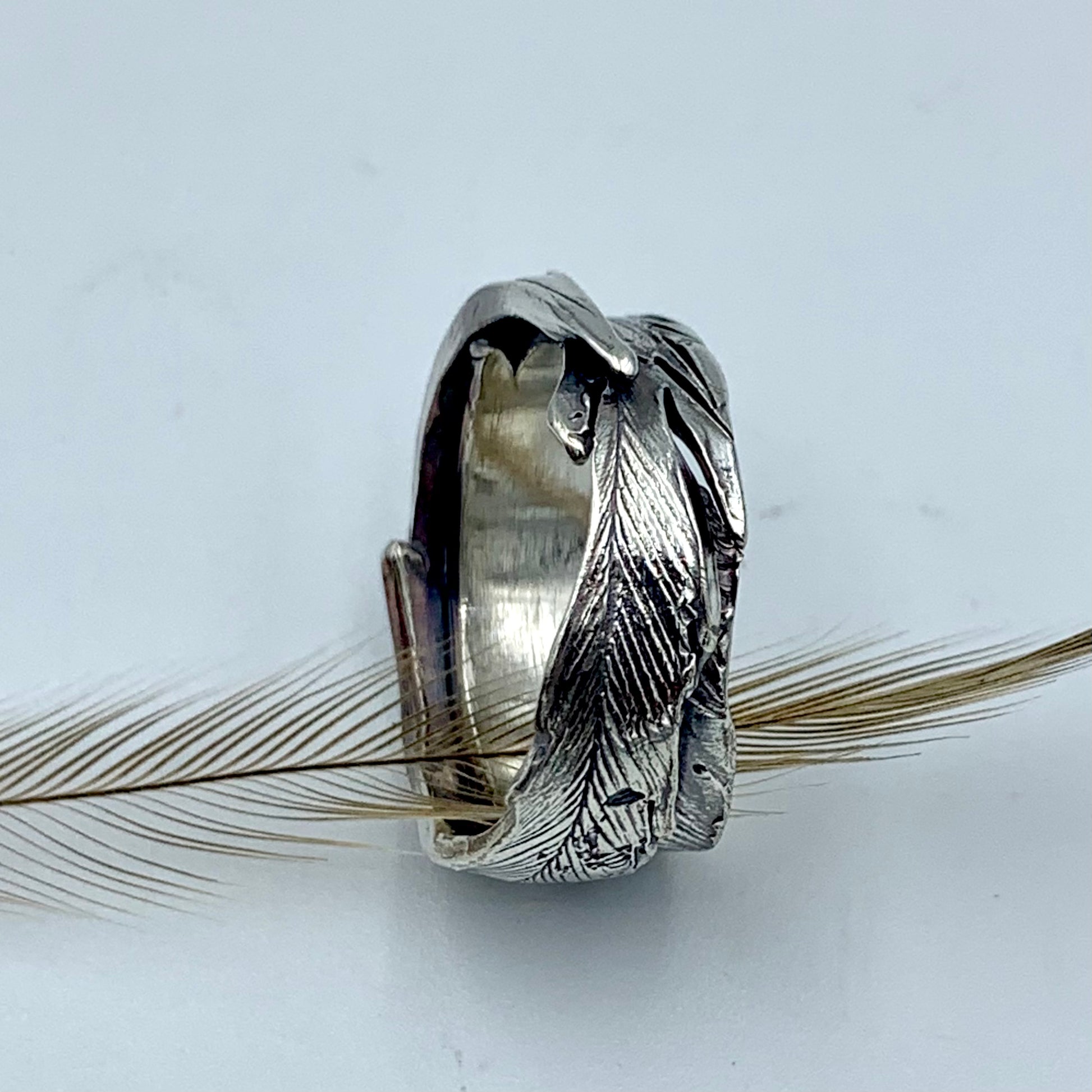 Sterling silver emu feather ring, angled view revealing polished interior band and sculptural feather exterior with oxidised shadow detail
