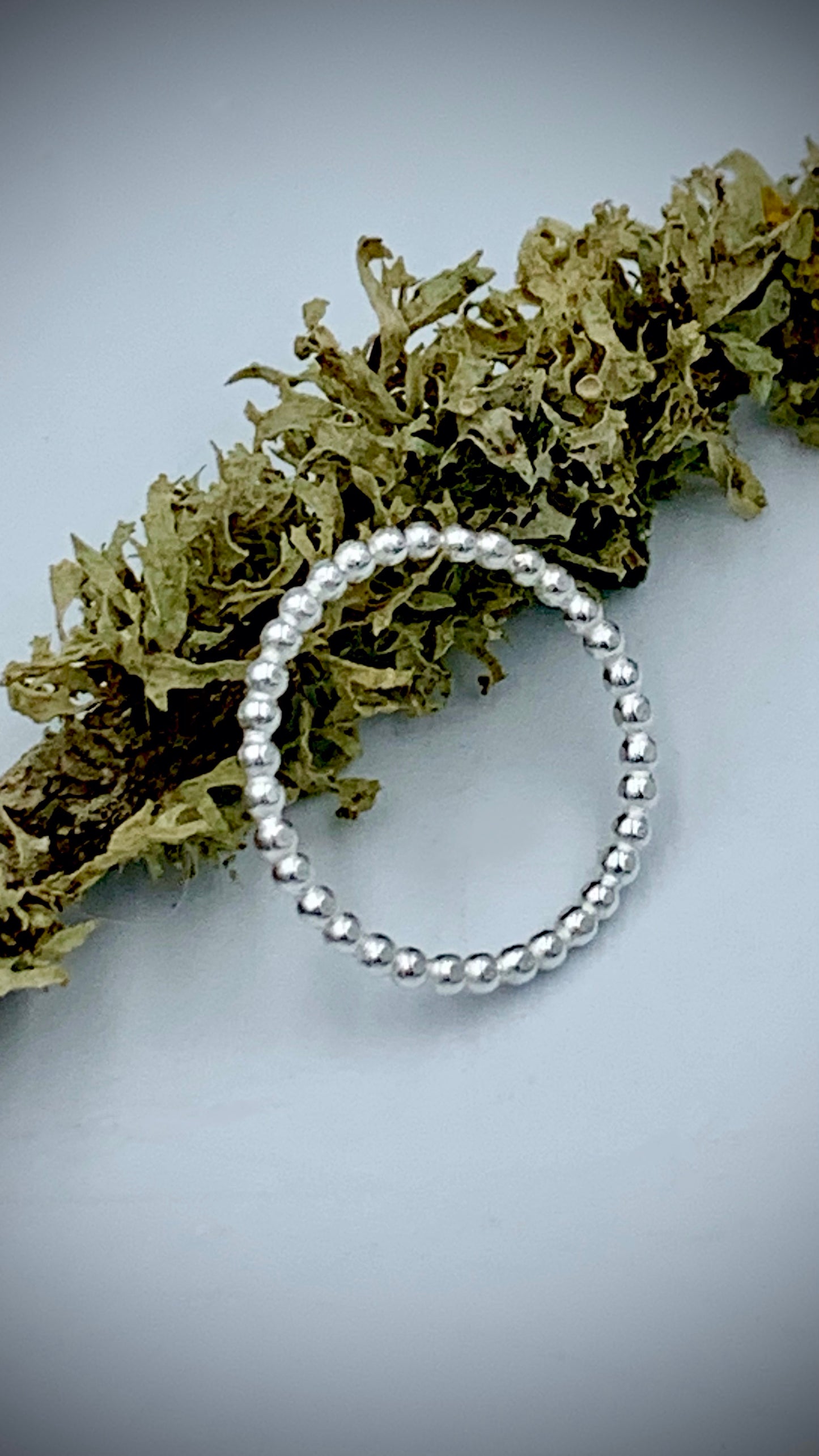 Sterling silver pearl bead stacking ring displayed on dried botanical foliage