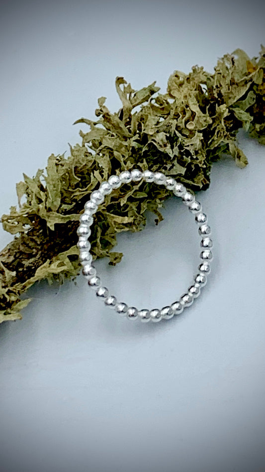 Sterling silver pearl bead stacking ring displayed on dried botanical foliage