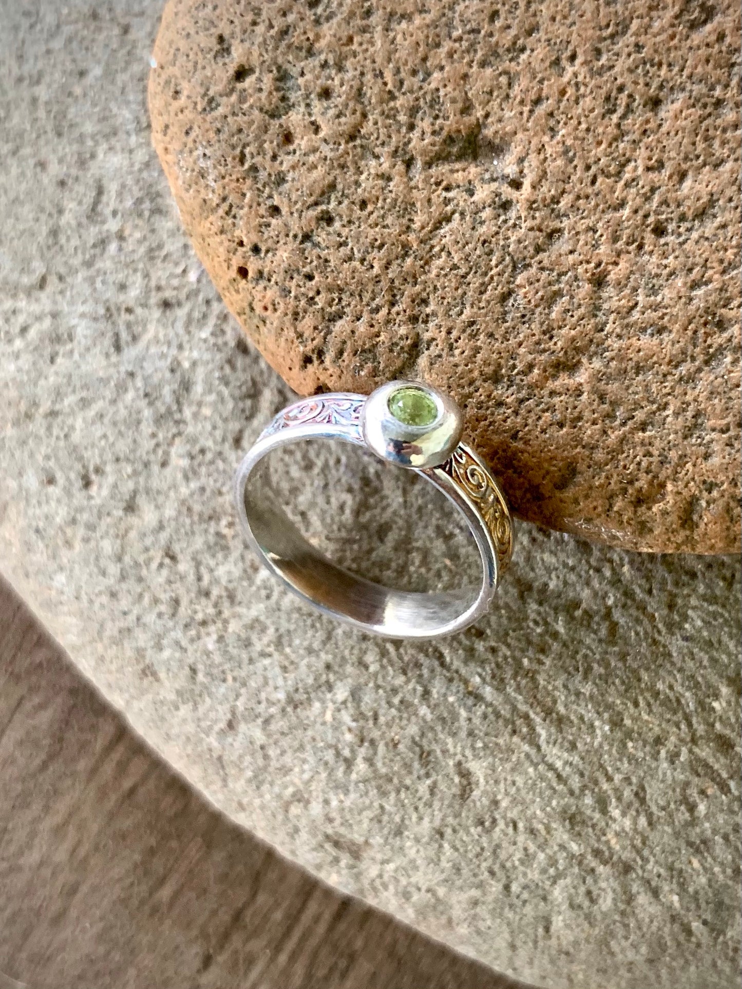 Sterling silver peridot ring displayed front-on with scroll band detail visible