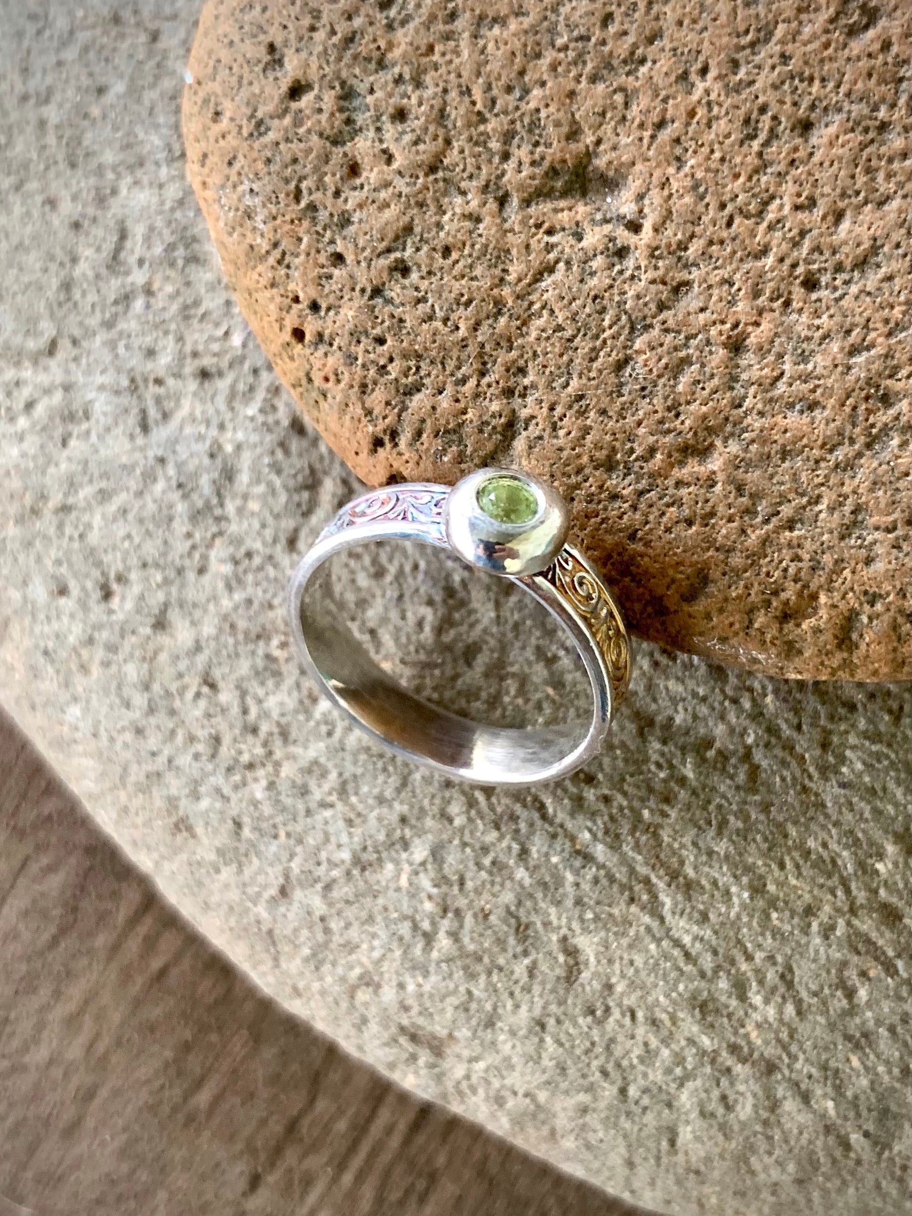 Sterling silver peridot ring displayed front-on with scroll band detail visible