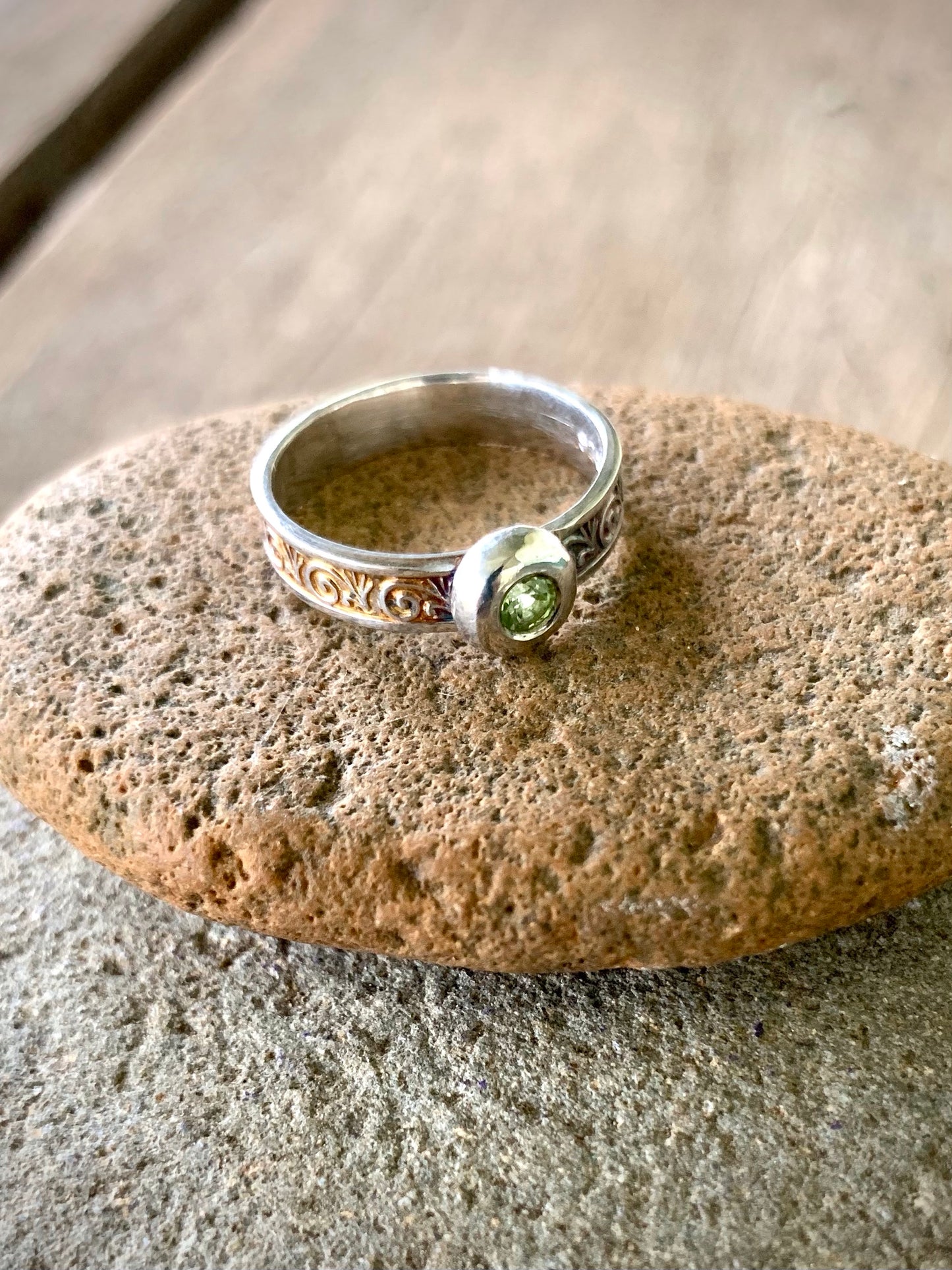 Sterling silver ring with flush-set peridot gemstone and scroll engraved band