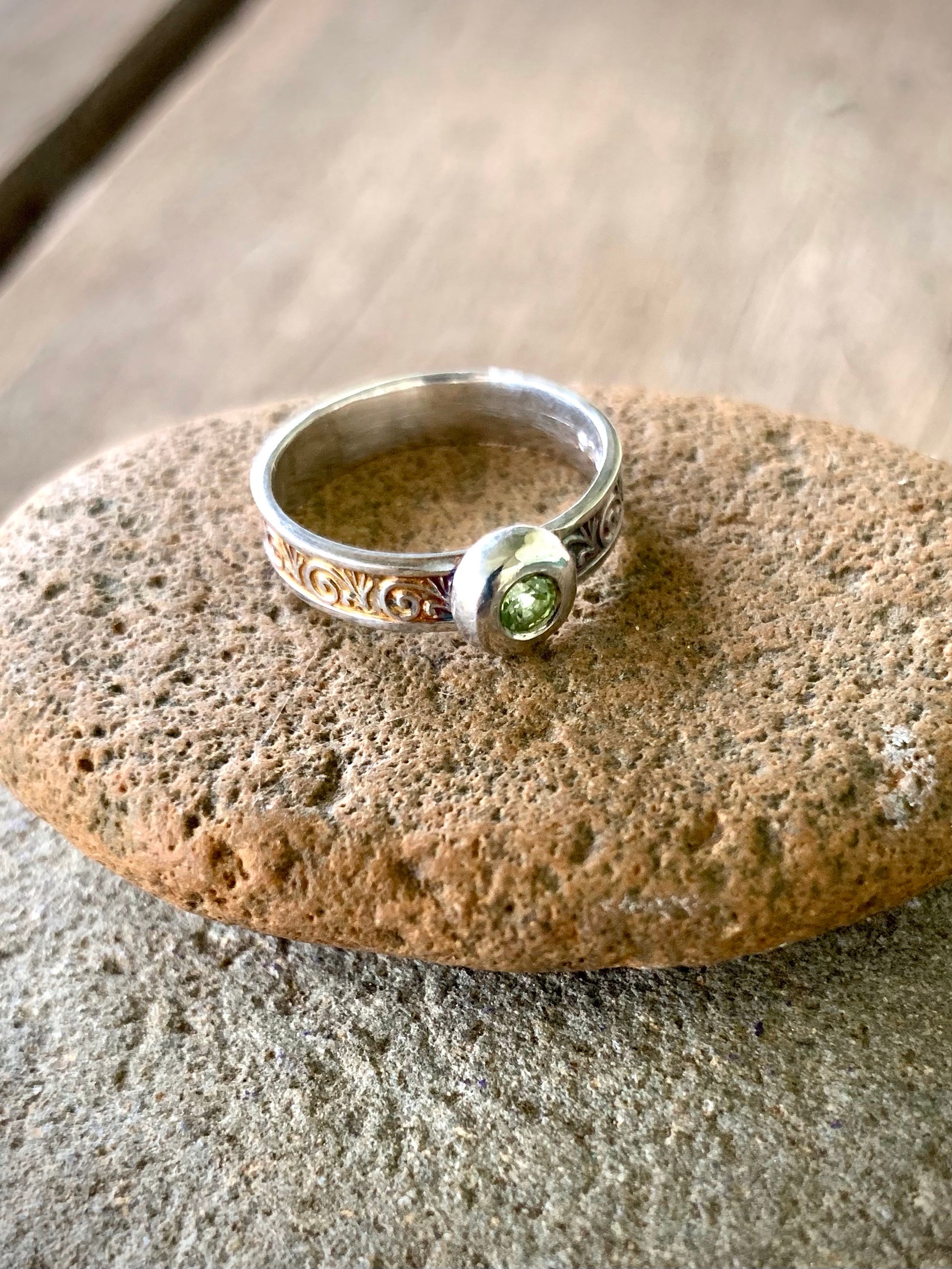 Sterling silver ring with flush-set peridot gemstone and scroll engraved band