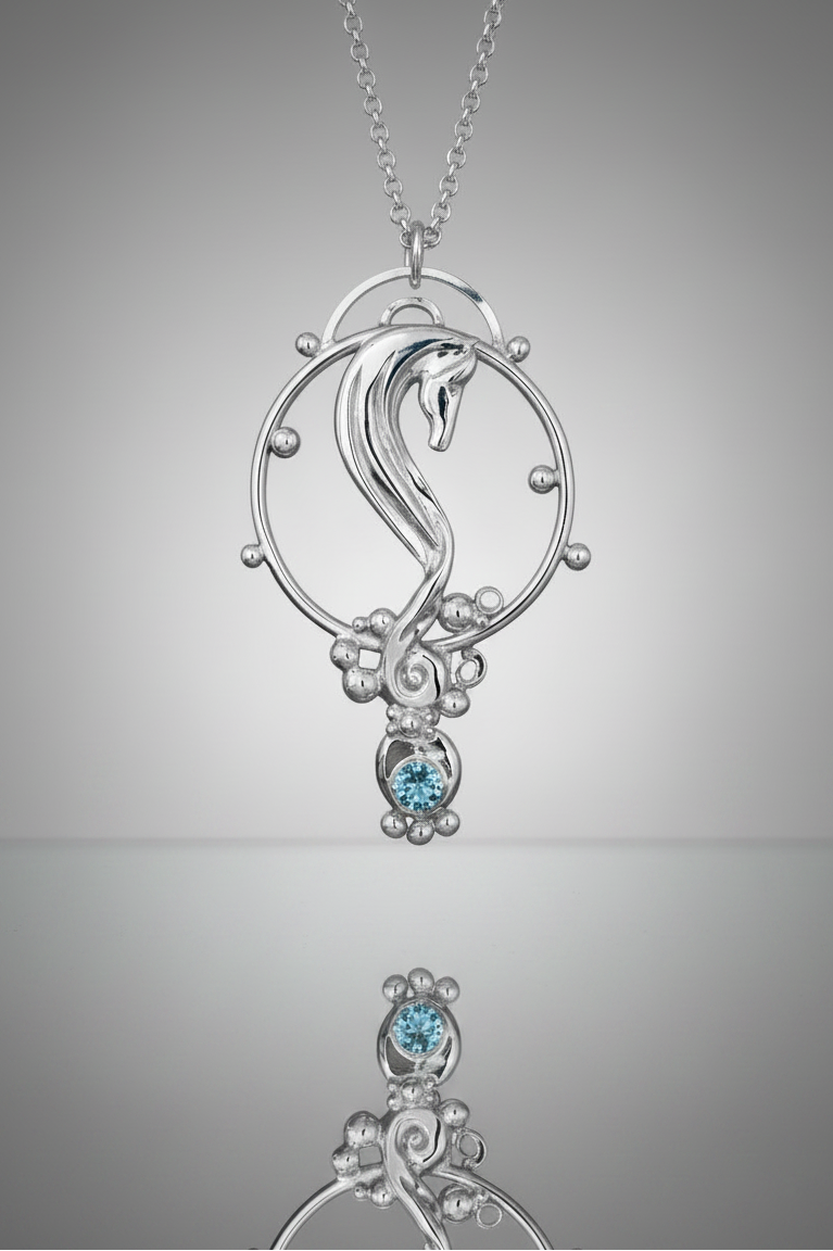 Sterling Silver Rhythm Horse seahorse pendant necklace with a Sky Blue Topaz gemstone, shown on a chain against a gray gradient background with a reflection below.