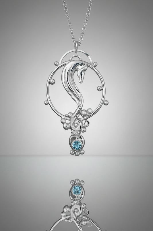 Sterling Silver Rhythm Horse seahorse pendant necklace with a Sky Blue Topaz gemstone, shown on a chain against a gray gradient background with a reflection below.