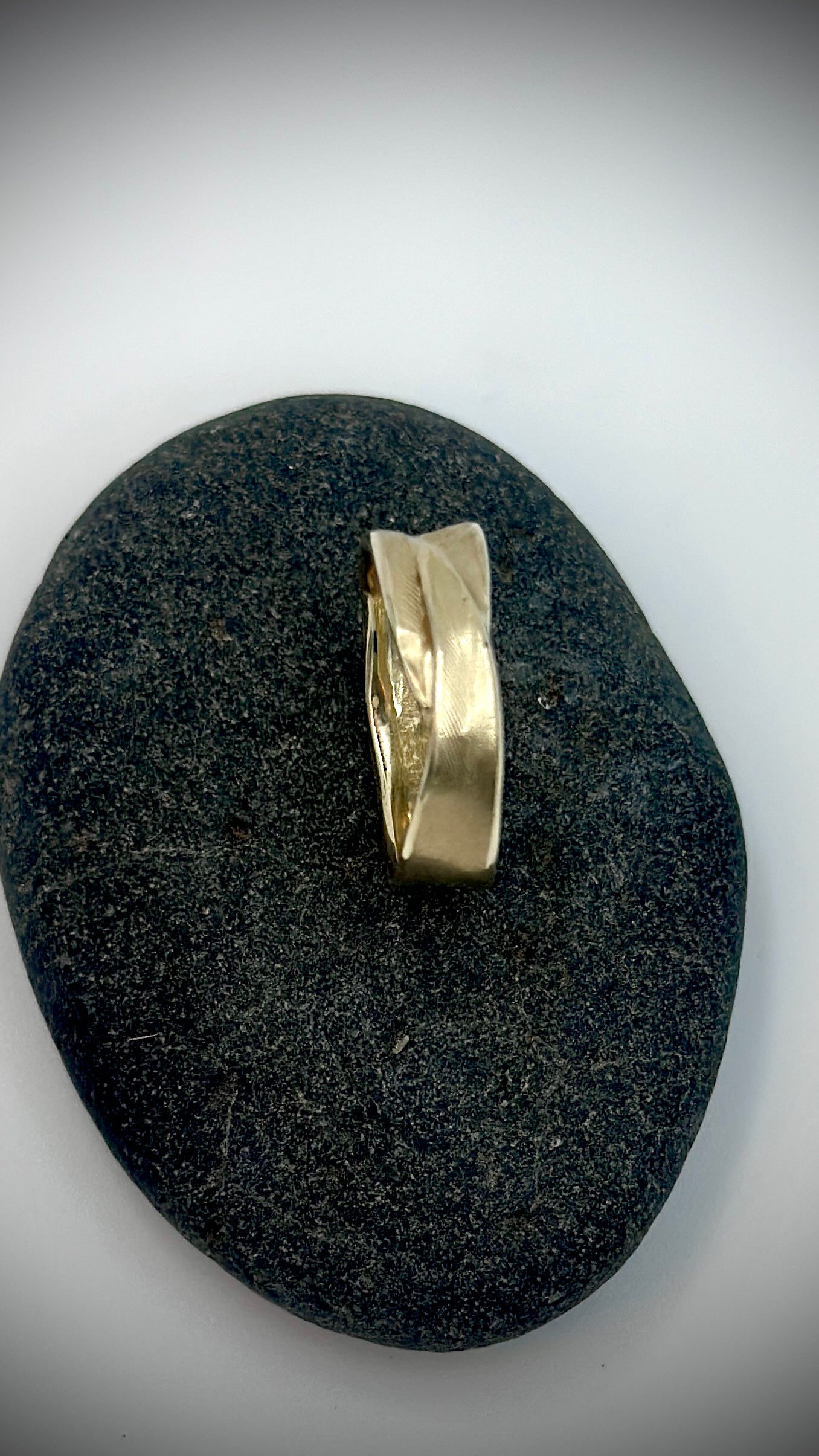 Top view of 9 carat gold feather ring resting on dark stone, revealing organic feather imprint across the band — Marina Fox Fine Art